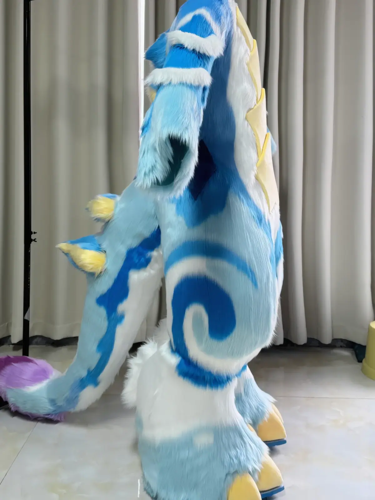 Kemono-style white and sky-blue horned dragon fullsuit with blue swirl markings, a digitigrade bodysuit and clawed feet paws, side view of the tail