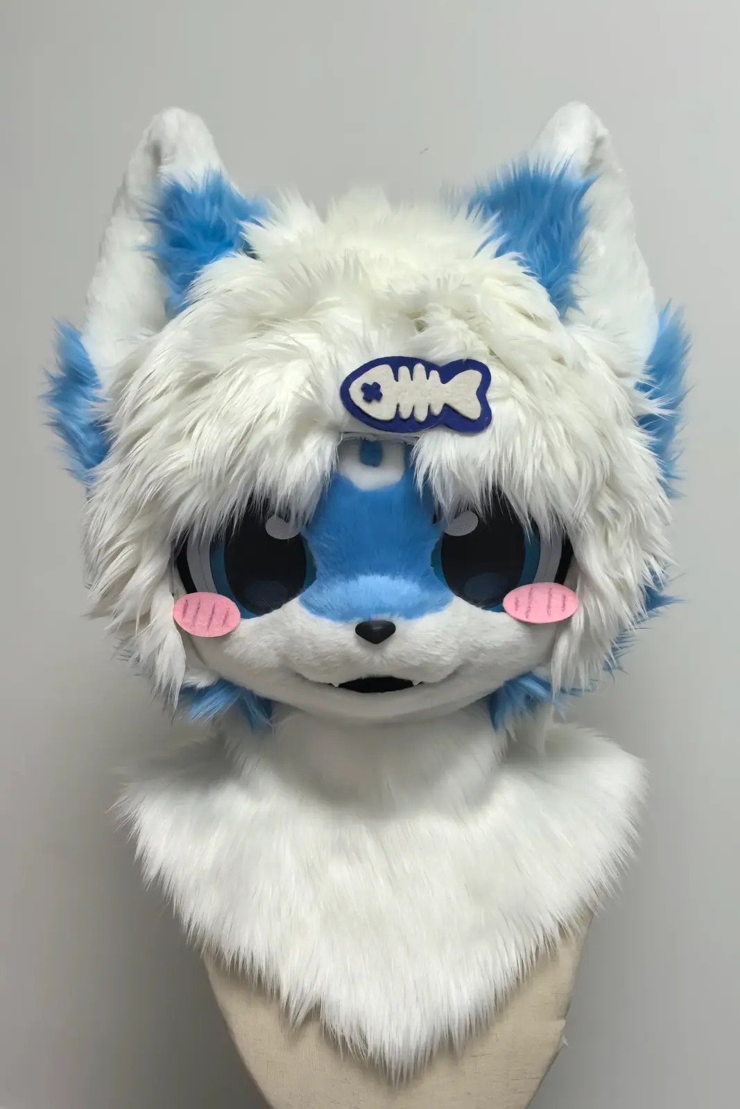 Kemono-style white fursuit head with a blue face, pink blush cheeks and a fish hair clip, front view