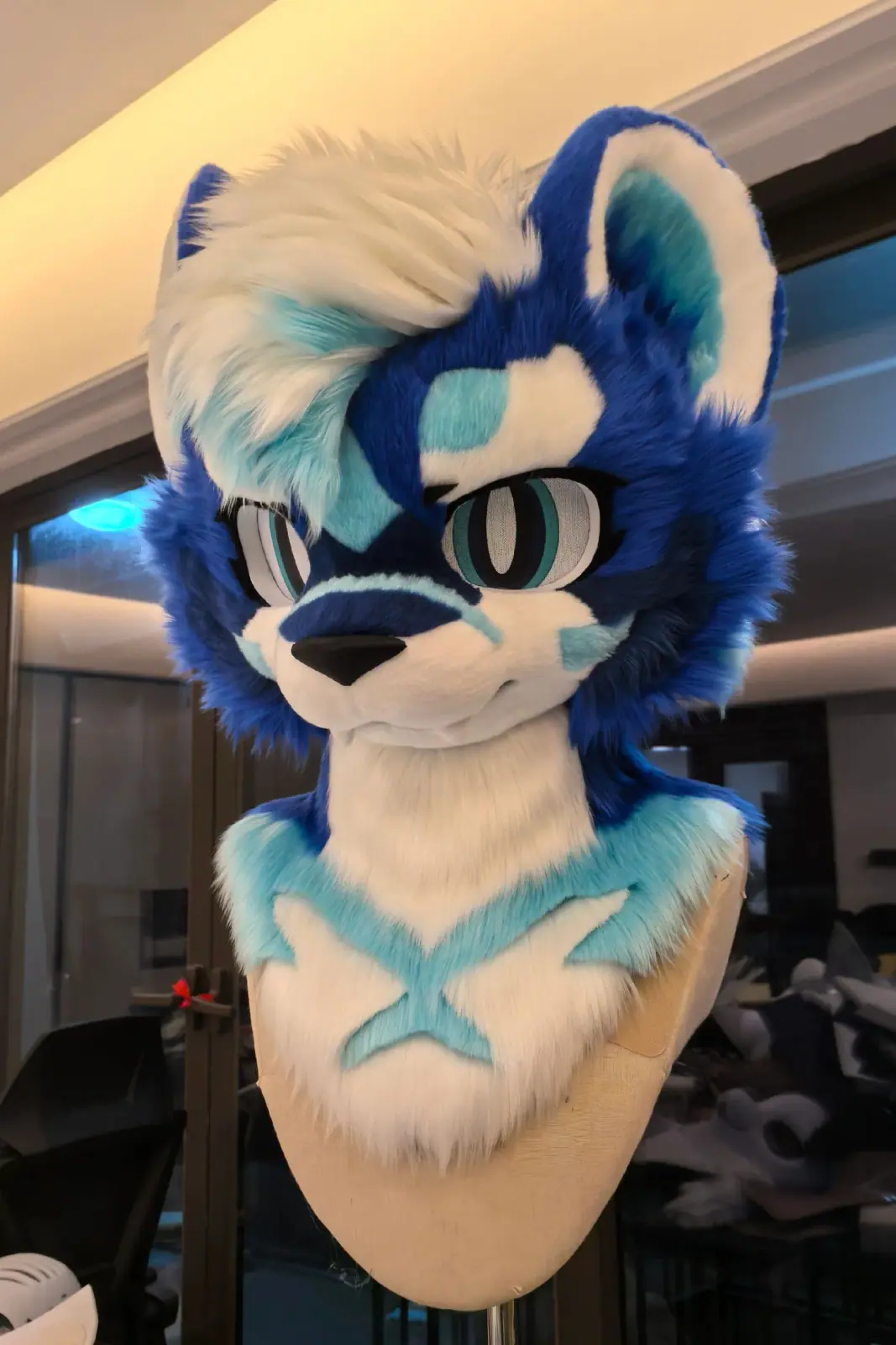 Toony-style blue and white husky fursuit head with teal markings, sharp anime eyes and a blue chest stripe, front view