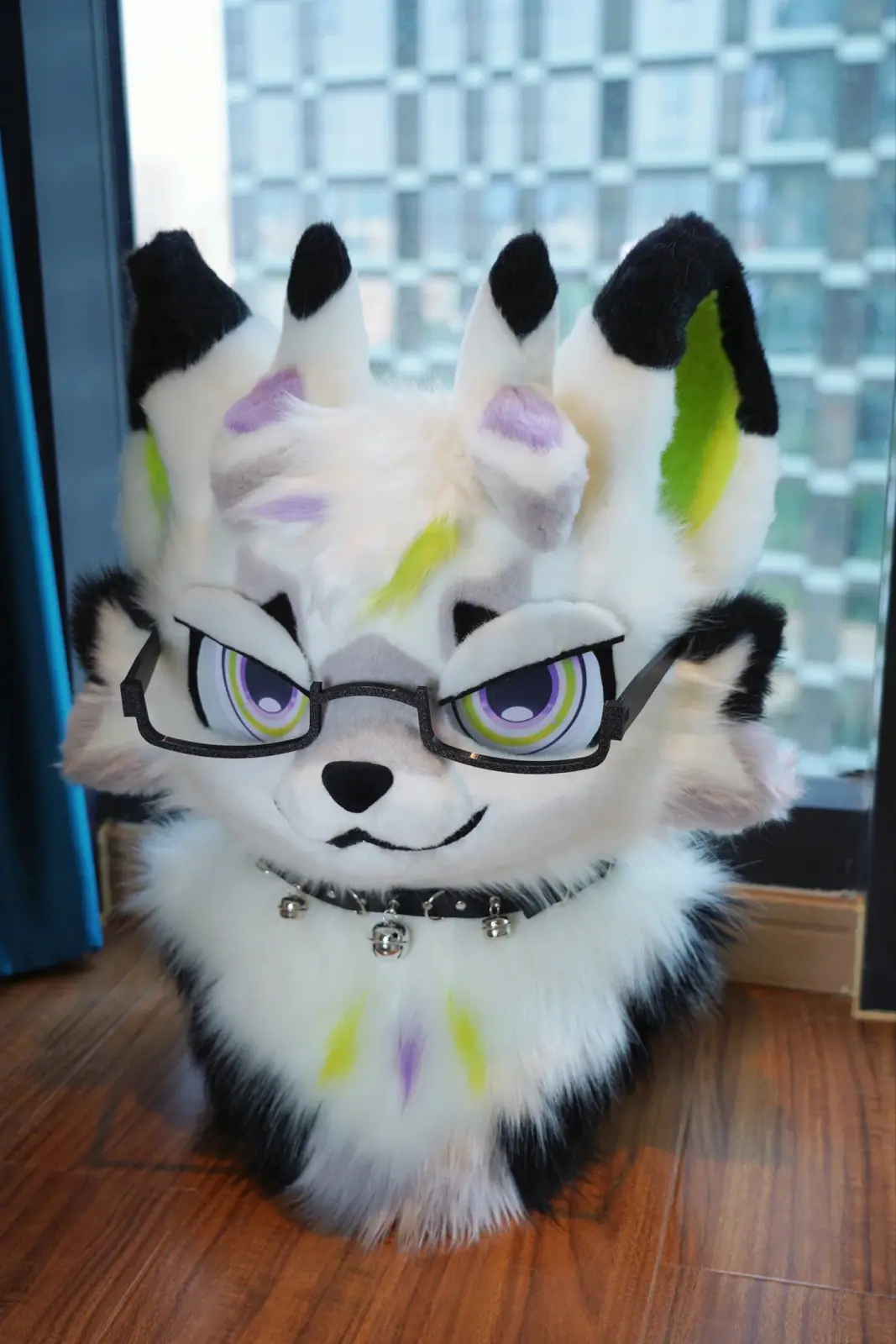 Toony-style cream and black fursuit head with four ears, lime and lilac accents, rainbow-ring eyes and black glasses, front view with glasses