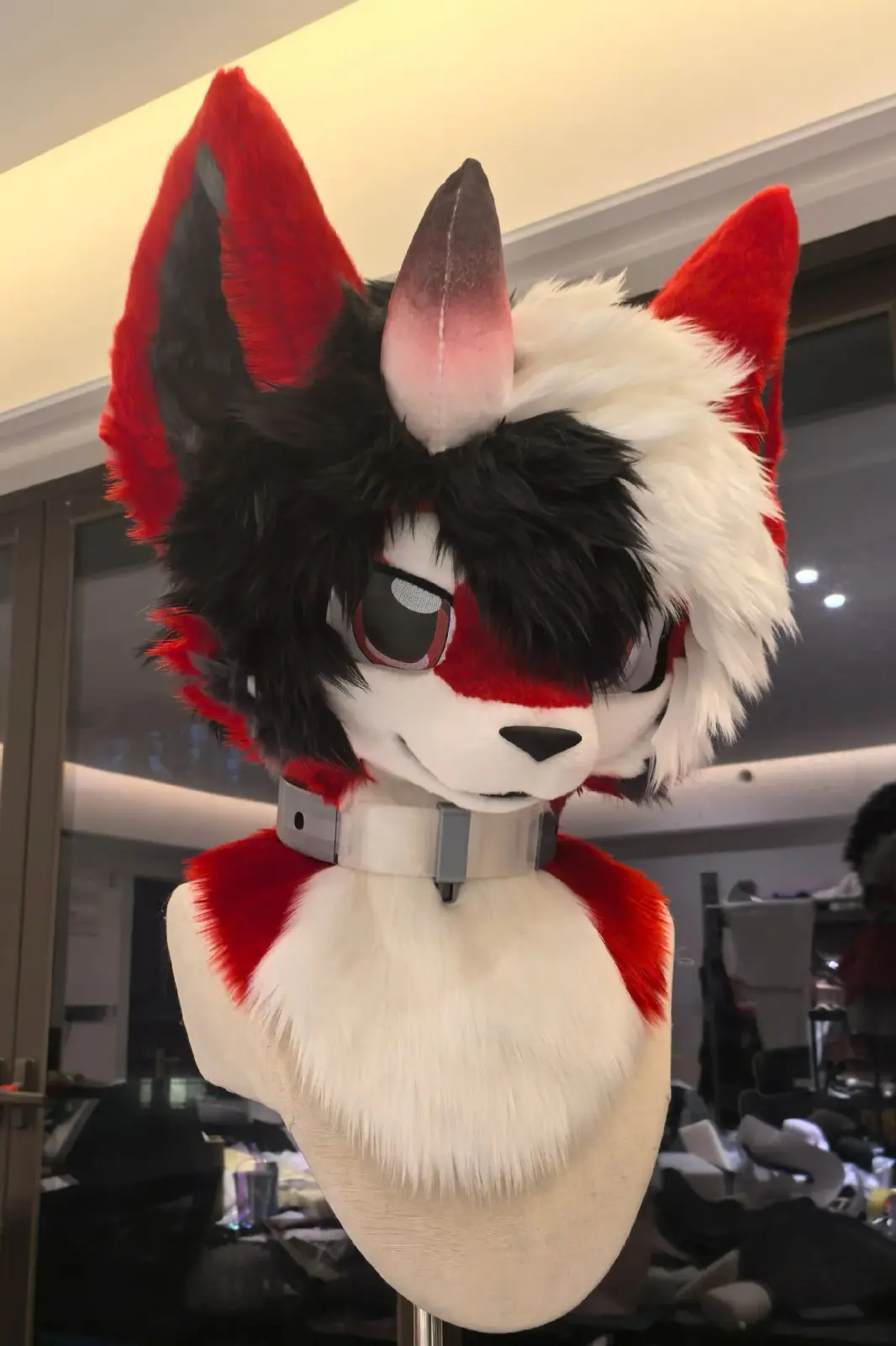 Toony-style black and white fox fursuit head with red ears, red markings and a silver collar, front view