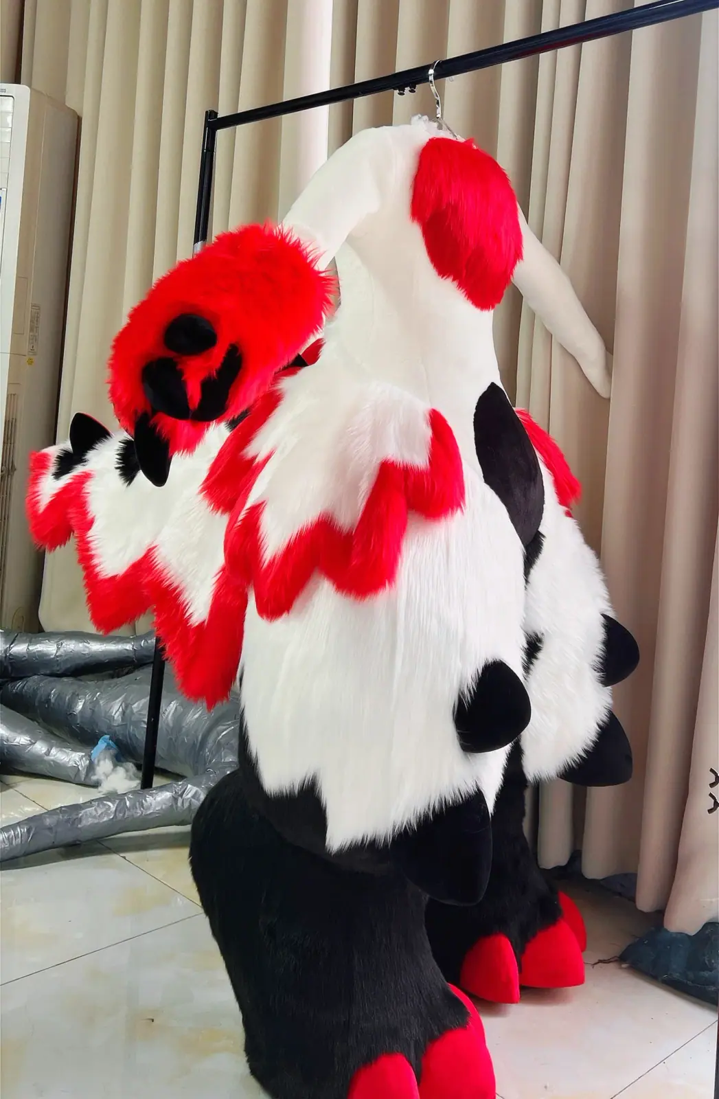 Red, white and black fursuit with jagged red trim and black legs, back view of the bodysuit