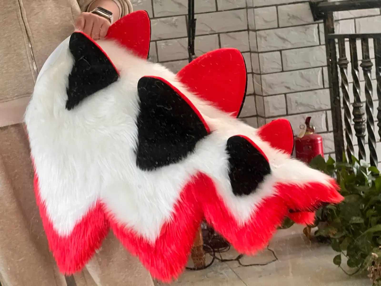 Red, white and black fursuit with jagged red trim and black legs, the matching tail laid flat