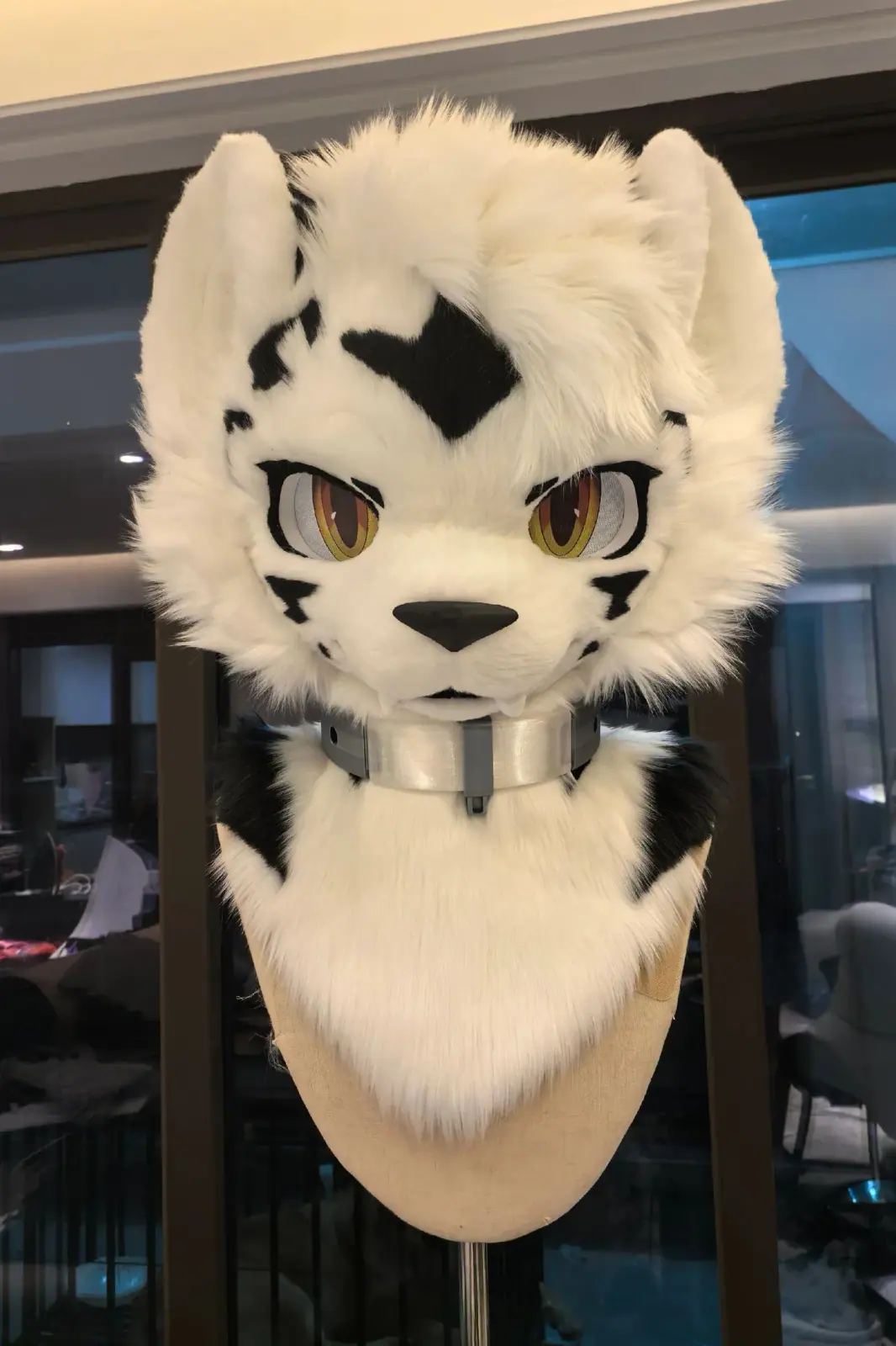 Toony-style white tiger fursuit head with black stripes, gold eyes and a silver collar, front view