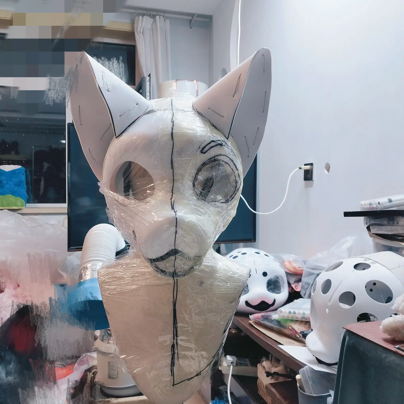 Fursuit head base, wrapped in film with seam lines drawn on, front view