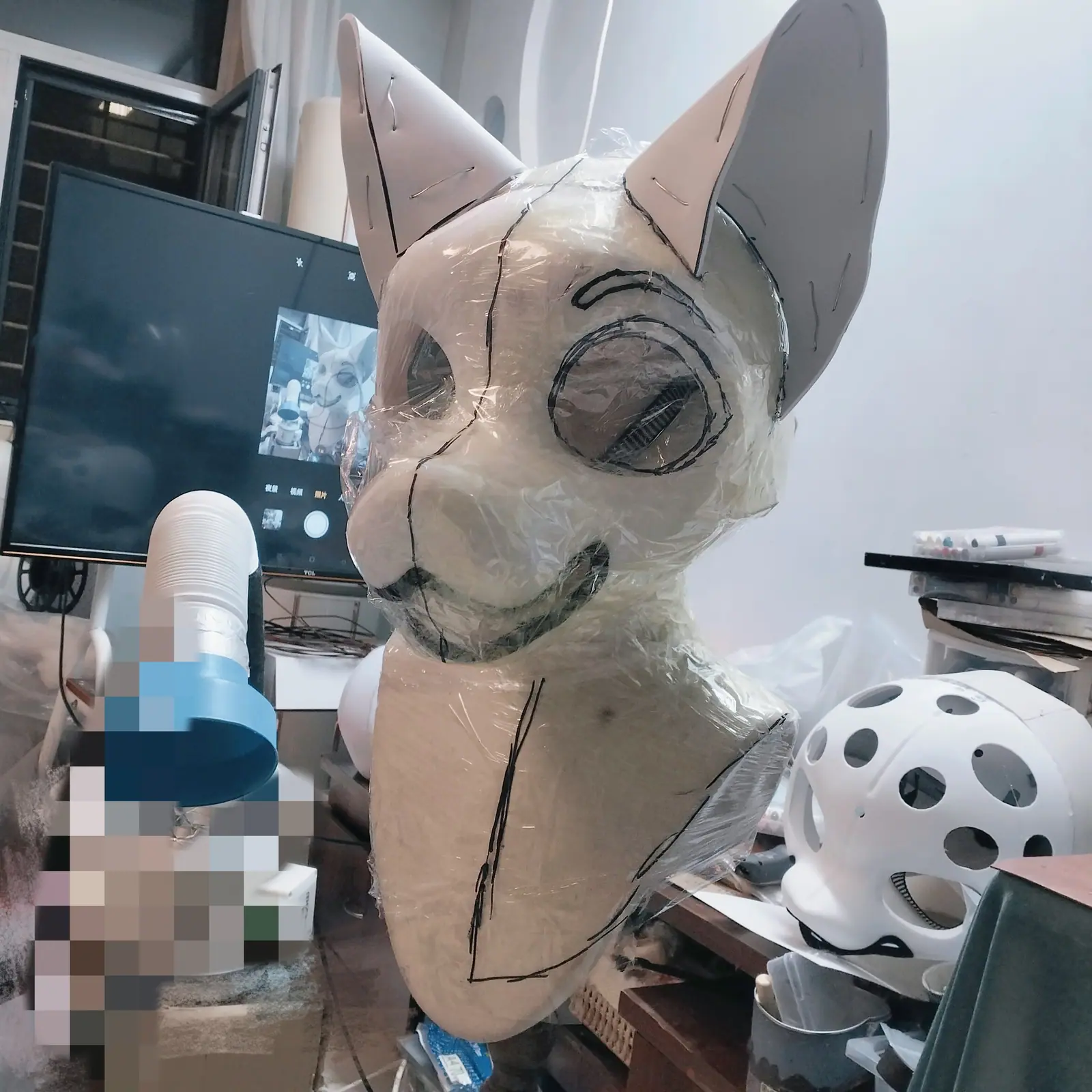 Fursuit head base, wrapped in film with seam lines drawn on, three-quarter view
